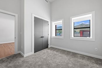 A room with a grey carpet, a white door, a grey wardrobe and a window with a view of the mountains at The Avenue Lofts Golden Apartments, Colorado, 80401